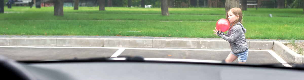 lekande barn framför bil på parkering